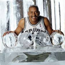 George Gervin posing with basketball trophies