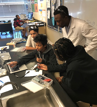 Three students working on laptop computer