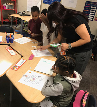 Teacher helping students at a table in a classroom