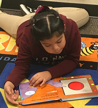 Female student reading a book on the floor