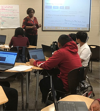 Teacher teaching students using laptops and a projector