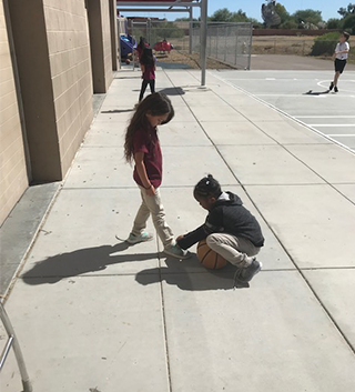 Female student helping another student tie their shoe